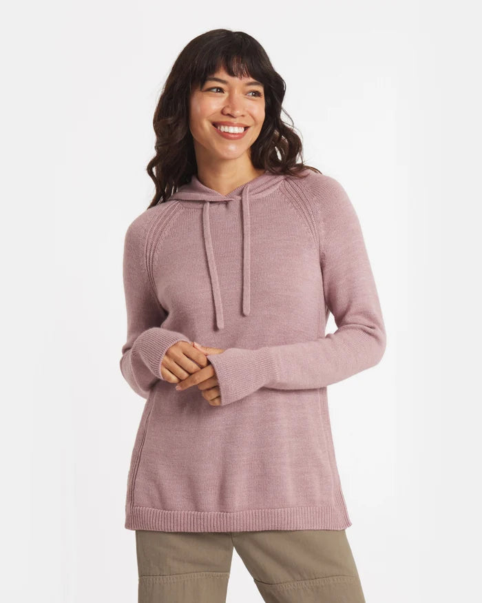 Three-quarter view of alpaca hoodie in dusty rose showing hood with drawstrings, raglan sleeves, and relaxed fit on model