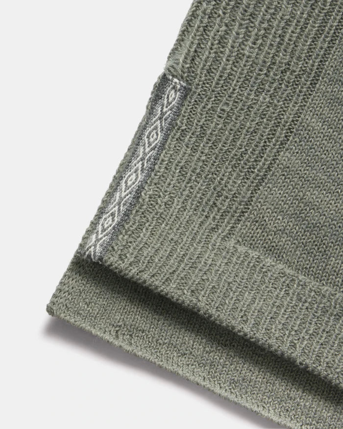Close-up of hem of women’s alpaca hoodie showing ribbed knit and contrasting diamond-pattern side trim on white background