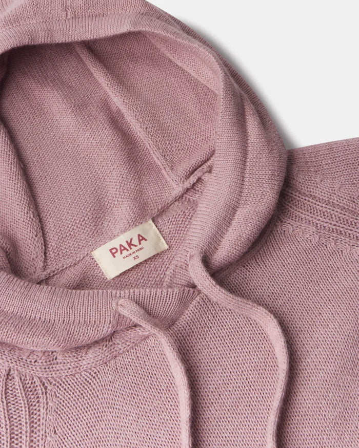 Close-up of women’s alpaca hoodie showing hood, drawstrings, knit texture, and PAKA label on pale gray background