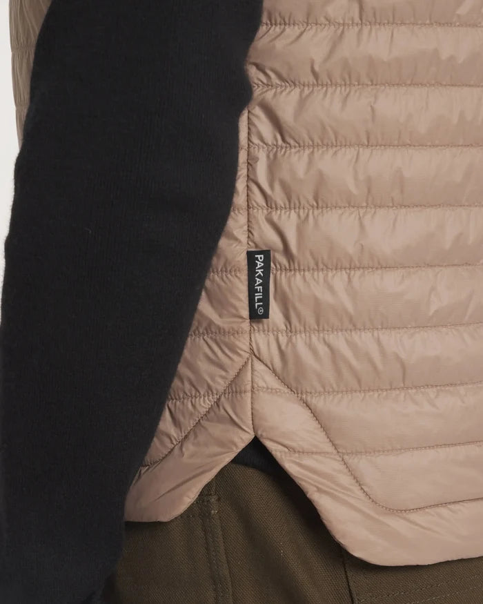 Close-up side-back of Women’s Mayu Ultralight Vest in Fossil showing quilted baffles, PAKAFILL tag, and curved hem on model
