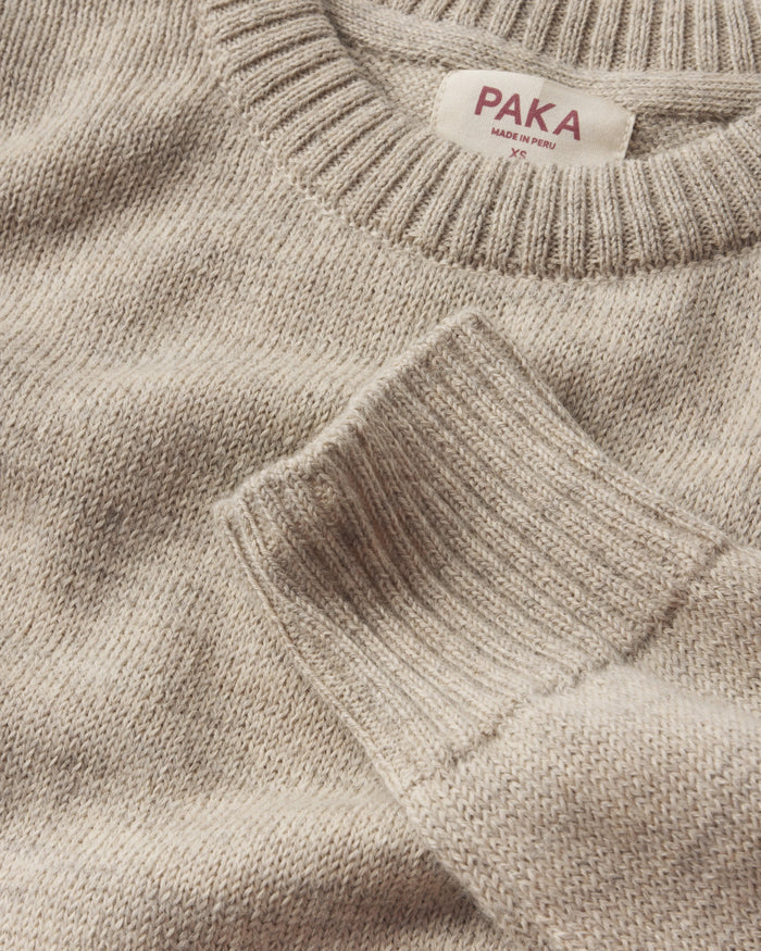 Close-up of a beige sweater with 'PAKA' label on a matching background