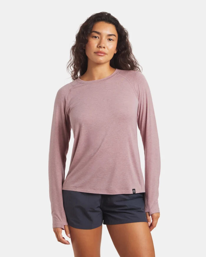 Woman wearing a long-sleeve pink shirt and black shorts on a white background