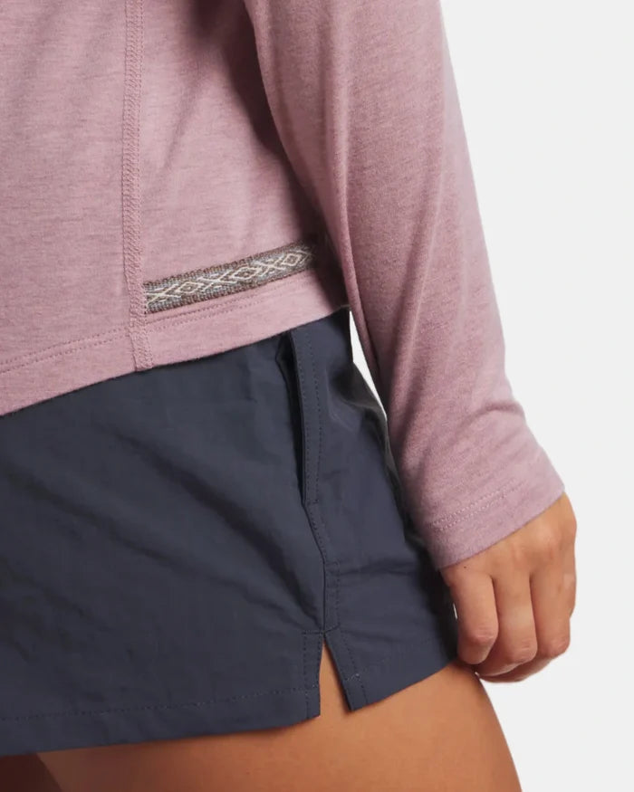 Person wearing a pink long-sleeve shirt and navy shorts on a white background