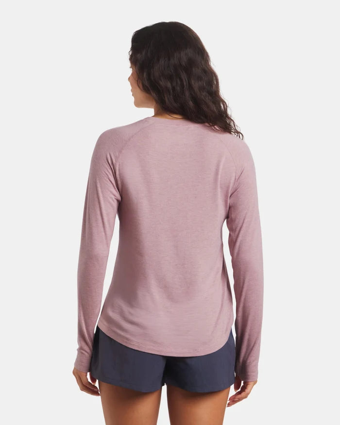 Woman wearing a pink long-sleeve shirt and navy shorts on a white background