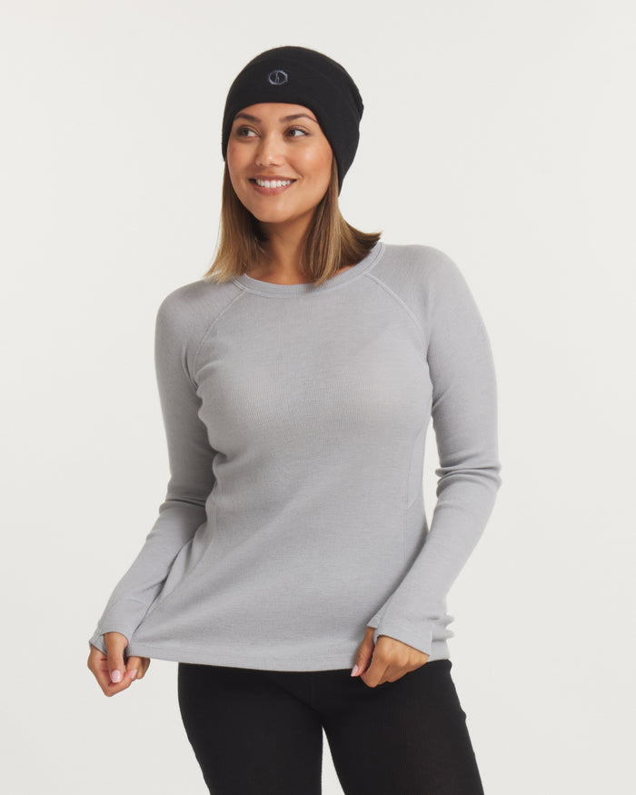 Front view of women’s thermal crew alpaca baselayer top in light gray on model; slim fit, raglan sleeves and thumbholes on white background