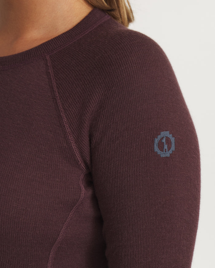 Close-up front-right of Women’s Thermal Crew alpaca baselayer top showcasing raglan seam and embroidered sleeve logo with light neutral background