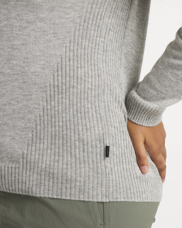 Close-up side view of Women’s Ultralight 1.0 Crew alpaca sweater showing ribbed side panel, PAKA tag, and model’s hand at hip