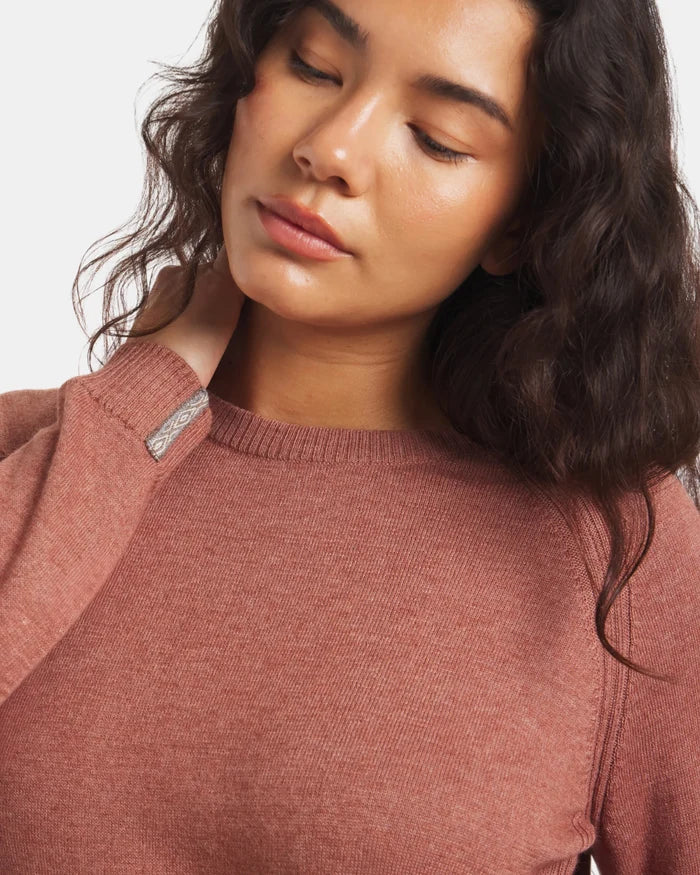Close-up of a person wearing a cinnamon sweater with a brand logo on a white background