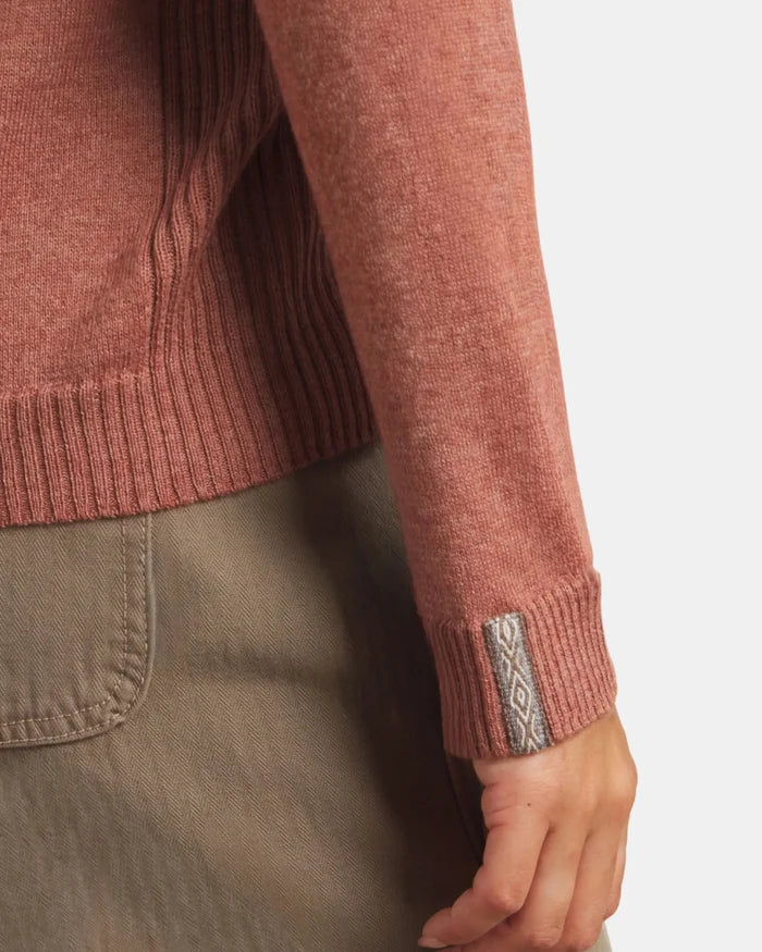 Close-up of a person wearing a brown sweater with a brand logo on a white background