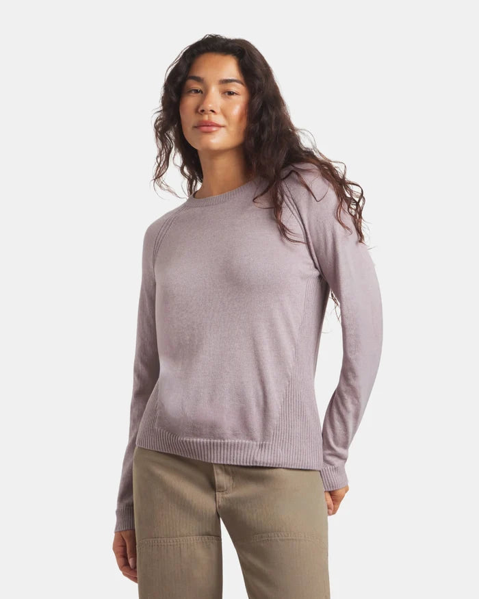 Woman wearing a light purple sweater and beige pants on a white background